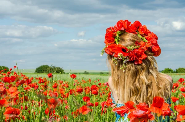 Young beautiful happy girl with long hair in a white dress in the poppy field with a wreath on his head — Stock Photo, Image