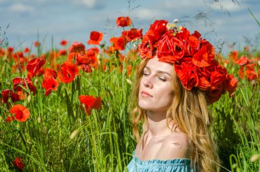 Kafasında bir çelenk ile haşhaş alanındaki beyaz elbiseli uzun saçlı genç güzel mutlu kız