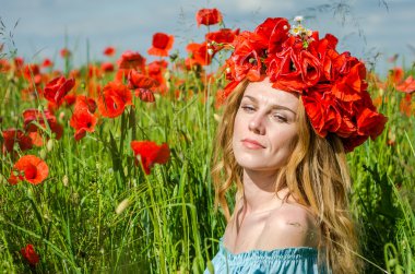 Kafasında bir çelenk ile haşhaş alanındaki beyaz elbiseli uzun saçlı genç güzel mutlu kız