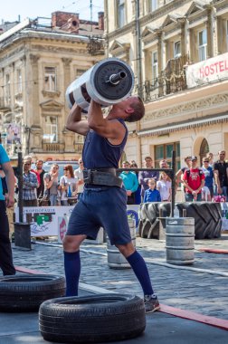 Lviv, Ukrayna - Haziran 2016: Spor formu vücut geliştirmeci olarak güçlü bir adam sokakta ağır bir halter kaldırıyor