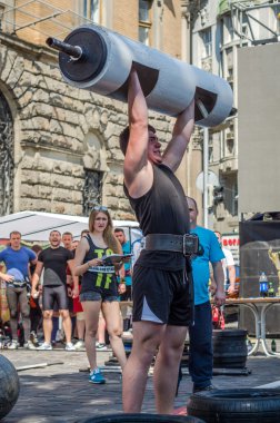 Lviv, Ukrayna - Haziran 2016: Spor formu vücut geliştirmeci olarak güçlü bir adam sokakta ağır bir halter kaldırıyor