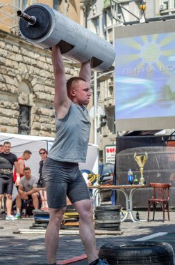 Lviv, Ukrayna - Haziran 2016: Spor formu vücut geliştirmeci olarak güçlü bir adam sokakta ağır bir halter kaldırıyor