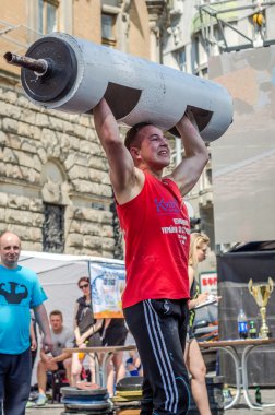 Lviv, Ukrayna - Haziran 2016: Spor formu vücut geliştirmeci olarak güçlü bir adam sokakta ağır bir halter kaldırıyor