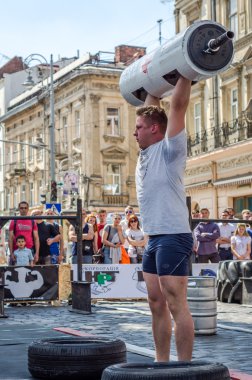 Lviv, Ukrayna - Haziran 2016: Spor formu vücut geliştirmeci olarak güçlü bir adam sokakta ağır bir halter kaldırıyor