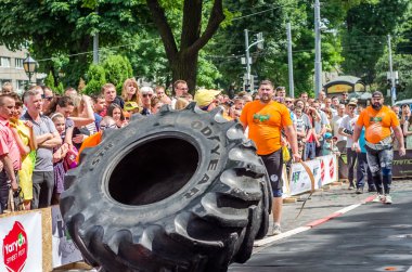Lviv, Ukrayna - Haziran 2016: Atlet vücut geliştirmeci diktatör güçlü gövdeli bir büyük bir kamyon lastik tekerlek dönme iter