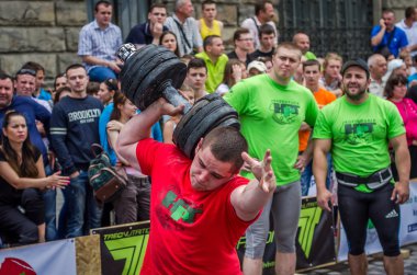 Lviv, Ukrayna - Haziran 2016: Güçlü adam atlet atletik şişirilmiş gövdeli bir şehir sokak ağır halter kaldırıyor