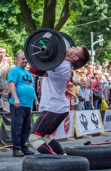 Lviv, Oekraïne - juni 2016: Atleet strongman opgeblazen met atletisch lichaam tillen van zware barbell op een stad straat — Stockfoto