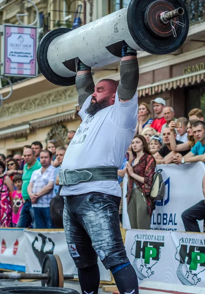 LVIV, UCRANIA - JUNIO 2016: Atleta hombre fuerte inflado con cuerpo atlético levantamiento de pesadas barras en una calle de la ciudad — Foto de Stock