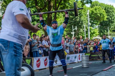 Lviv, Ukrayna - Haziran 2016: Güçlü atlet vücut geliştirmeci diktatör bir şehir sokak seyirci önünde ağır bir halter kaldırıyor