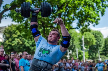 Lviv, Ukrayna - Haziran 2016: Güçlü atlet vücut geliştirmeci diktatör bir şehir sokak seyirci önünde ağır halter kaldırıyor