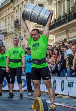 Lviv, Ukrayna - Haziran 2016: Güçlü atlet vücut geliştirmeci diktatör bir şehir sokak alüminyum varil bira kitleye asansörleri