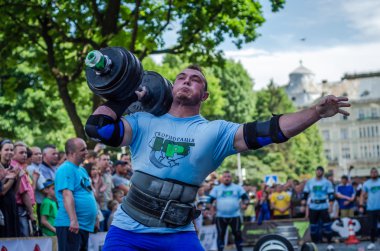 Lviv, Ukrayna - Haziran 2016: Güçlü atlet vücut geliştirmeci diktatör bir şehir sokak seyirci önünde ağır halter kaldırıyor
