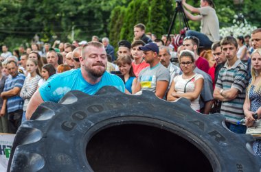 Lviv, Ukrayna - Haziran 2016: Güçlü vücut geliştirmeci atlet, atlet şaşkın kamu önünde sokakta kamyondan büyük bir siyah Goodyear tekerleği rulo