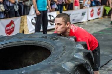 Lviv, Ukrayna - Haziran 2016: Güçlü vücut geliştirmeci atlet, atlet şaşkın kamu önünde sokakta kamyondan büyük bir siyah Goodyear tekerleği rulo
