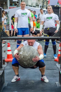 Lviv, Ukrayna - Haziran 2016: Güçlü vücut geliştirmeci strongman mermerden yapılmış büyük bir ağır taş topu kaldırır ve şaşkın seyircilerin gözleri altında sokakta bar üzerine atar