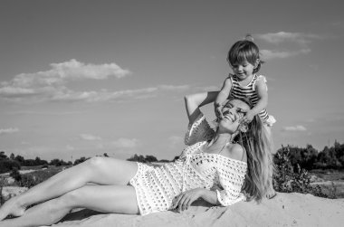 Genç çekici güzel anne ile kızının oynarken ve kumlu bir plaj üzerinde göl, mutlu bir aile olarak bir neşeli duygular eğleniyor