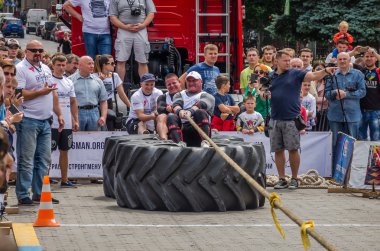 Lviv, Ukrayna - Temmuz 2016: güçlü atlet diktatör bir ortakla oturan bir ip kamyon çekerek büyük lastikler değil