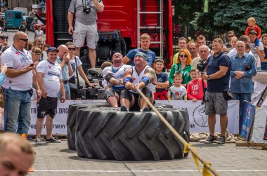 Lviv, Ukrayna - Temmuz 2016: güçlü atlet diktatör bir ortakla oturan bir ip kamyon çekerek büyük lastikler değil