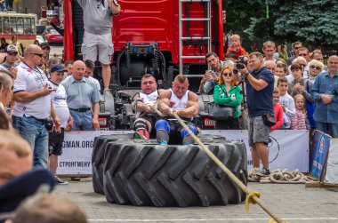 Lviv, Ukrayna - Temmuz 2016: güçlü atlet diktatör bir ortakla oturan bir ip kamyon çekerek büyük lastikler değil