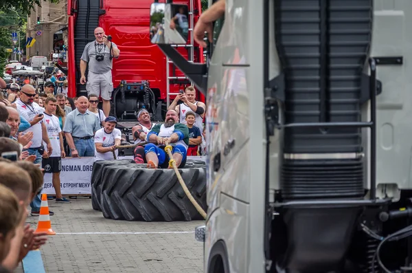 Lviv, Ukrayna - Temmuz 2016: güçlü atlet diktatör bir ortakla oturan bir ip kamyon çekerek büyük lastikler değil