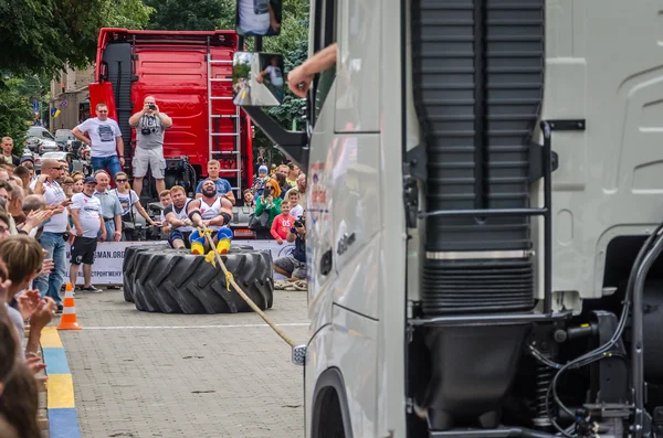 Lviv, Ukrayna - Temmuz 2016: güçlü atlet diktatör bir ortakla oturan bir ip kamyon çekerek büyük lastikler değil