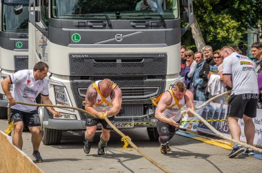 Lviv, Ukrayna - Temmuz 2016: İki güçlü atlet vücut geliştirmeci strongman hevesli izleyicilerin önünde halatlar iki büyük kamyon ile çekerek