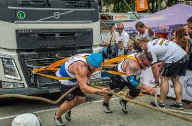 Lviv, Ukrayna - Temmuz 2016: İki güçlü atlet vücut geliştirmeci strongman hevesli izleyicilerin önünde halatlar iki büyük kamyon ile çekerek