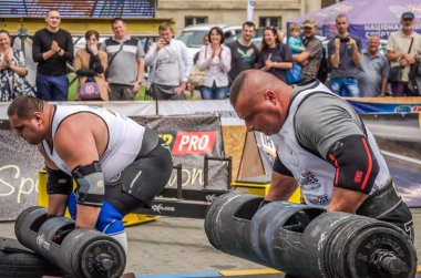 Lviv, Ukrayna - Temmuz 2016: güçlü atlet vücut geliştirmeci diktatör ağır beden ile pompalanır güneşli bir günde bir paket sokakta coşkulu seyirci önünde çıtayı yükseltiyor