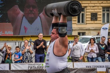 Lviv, Ukrayna - Temmuz 2016: güçlü atlet vücut geliştirmeci diktatör ağır beden ile pompalanır güneşli bir günde bir paket sokakta coşkulu seyirci önünde çıtayı yükseltiyor