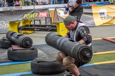 Lviv, Ukrayna - Temmuz 2016: güçlü atlet vücut geliştirmeci diktatör ağır beden ile pompalanır güneşli bir günde bir paket sokakta coşkulu seyirci önünde çıtayı yükseltiyor