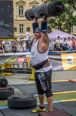 Lviv, Ukrayna - Temmuz 2016: güçlü atlet vücut geliştirmeci diktatör ağır beden ile pompalanır güneşli bir günde bir paket sokakta coşkulu seyirci önünde çıtayı yükseltiyor