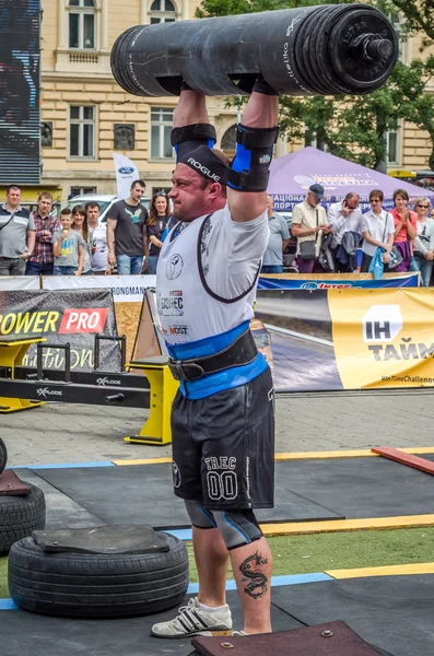 Lviv, Ukrayna - Temmuz 2016: güçlü atlet vücut geliştirmeci diktatör ağır beden ile pompalanır güneşli bir günde bir paket sokakta coşkulu seyirci önünde çıtayı yükseltiyor