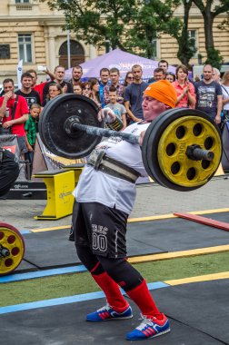Lviv, Ukrayna - Temmuz 2016: güçlü atlet vücut geliştirmeci diktatör ağır beden ile pompalanır güneşli bir günde bir paket sokakta coşkulu seyirci önünde çıtayı yükseltiyor