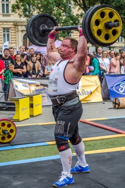 Lviv, Ukrayna - Temmuz 2016: güçlü atlet vücut geliştirmeci diktatör ağır beden ile pompalanır güneşli bir günde bir paket sokakta coşkulu seyirci önünde çıtayı yükseltiyor