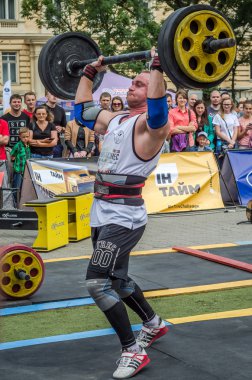 Lviv, Ukrayna - Temmuz 2016: güçlü atlet vücut geliştirmeci diktatör ağır beden ile pompalanır güneşli bir günde bir paket sokakta coşkulu seyirci önünde çıtayı yükseltiyor