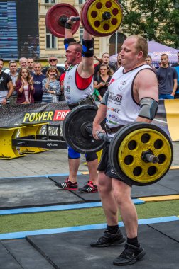 Lviv, Ukrayna - Temmuz 2016: güçlü atlet vücut geliştirmeci diktatör ağır beden ile pompalanır güneşli bir günde bir paket sokakta coşkulu seyirci önünde çıtayı yükseltiyor