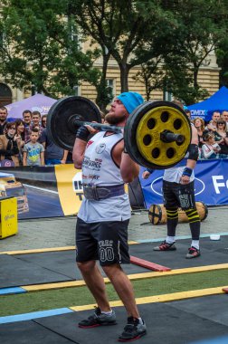 Lviv, Ukrayna - Temmuz 2016: güçlü atlet vücut geliştirmeci diktatör ağır beden ile pompalanır güneşli bir günde bir paket sokakta coşkulu seyirci önünde çıtayı yükseltiyor