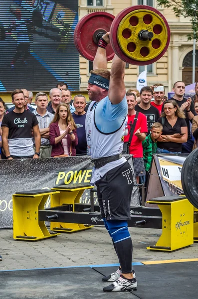 Lviv, Ukrayna - Temmuz 2016: güçlü atlet vücut geliştirmeci diktatör ağır beden ile pompalanır güneşli bir günde bir paket sokakta coşkulu seyirci önünde çıtayı yükseltiyor