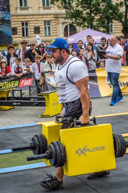 Çok güçlü atlet vücut geliştirmeci diktatör coşkulu seyirci önünde sokakta ağır demir bavul taşır
