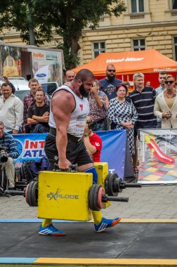 Çok güçlü atlet vücut geliştirmeci diktatör coşkulu seyirci önünde sokakta ağır demir bavul taşır