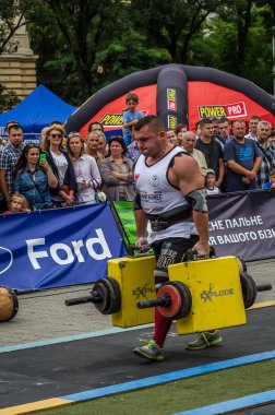 Çok güçlü atlet vücut geliştirmeci diktatör coşkulu seyirci önünde sokakta ağır demir bavul taşır
