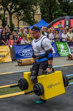 Çok güçlü atlet vücut geliştirmeci diktatör coşkulu seyirci önünde sokakta ağır demir bavul taşır
