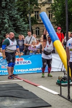Çok güçlü atlet vücut geliştirmeci diktatör coşkulu seyirci önünde sokakta ağır demir bavul taşır