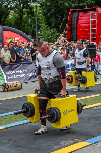 Poderoso atleta fuerte culturista hombre fuerte lleva pesadas maletas de hierro en la calle delante de espectadores entusiastas — Foto de Stock