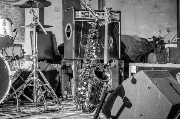 Золотой саксофон стоит на сцене рядом с другими музыкальными инструментами — стоковое фото
