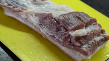 Şef kesme tahtasındaki bıçakla domuz göbeği kesiyor.