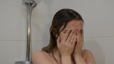Genç ve çekici bir kadın duşta maskarasını temizler.
