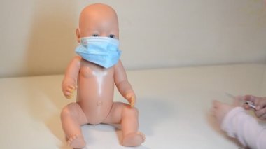 Küçük kız bebeğine iğne yapıyor, doktorculuk oynuyor.