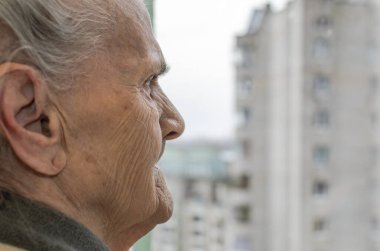 Pencereden dışarı bakan yaşlı bir kadın.