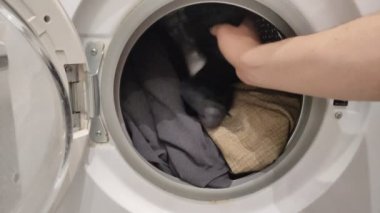 Temizlikçi kirli çamaşırları çamaşır makinesine yüklüyor.